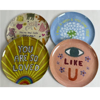 Four colorful ceramic plates with various designs and text on a white background