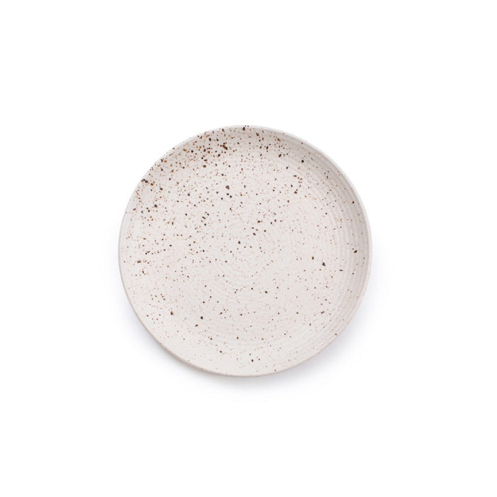 A round ceramic plate with a speckled beige and brown glaze, photographed from directly above on a solid white background.