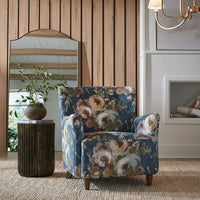 Floral patterned armchair in a room with wooden walls and a mirror.