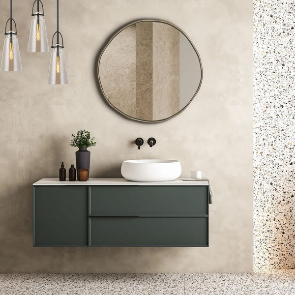 Bathroom vanity with round mirror, sink, and decorative items against a beige wall.