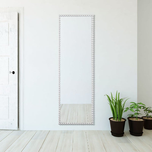 White decorative mirror on a white wall with potted plants below