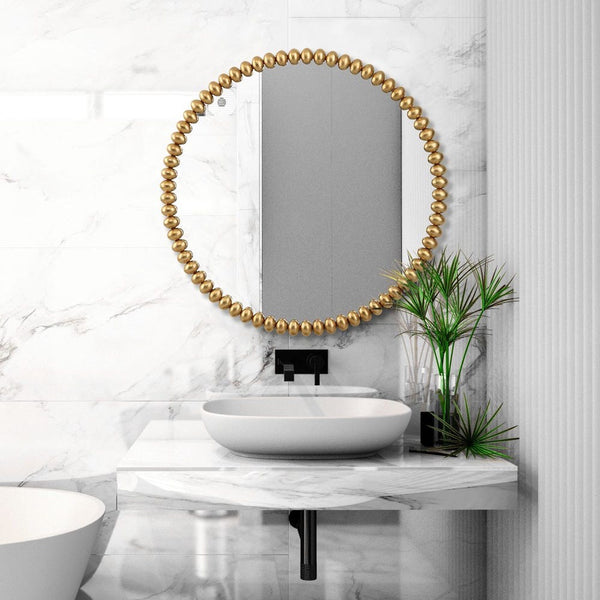 Bathroom with a round mirror with a gold bead frame, sink, and plant.