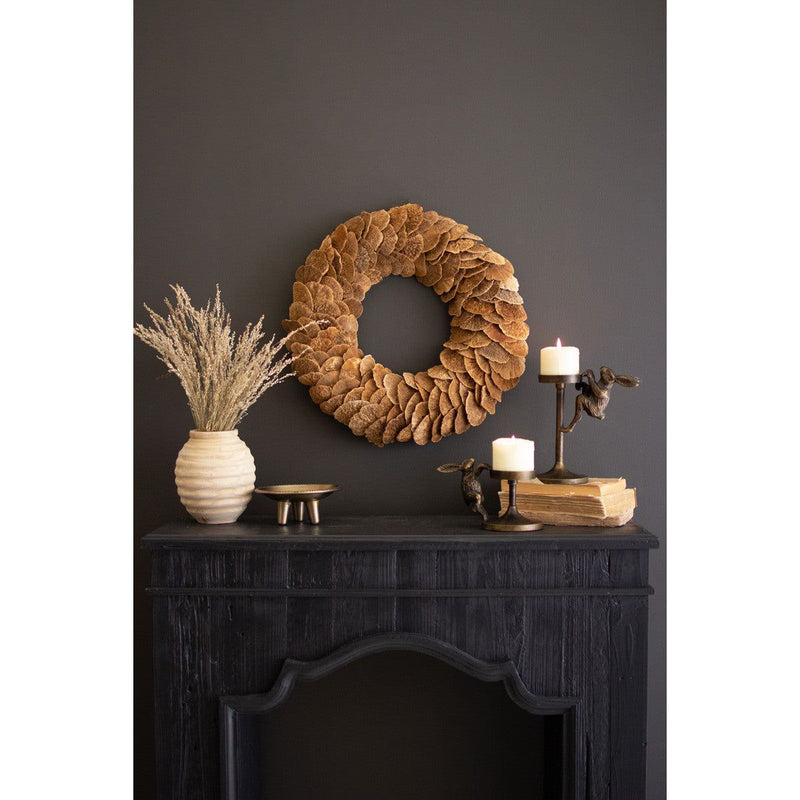 Dark mantle featuring a stunning Mushroom Sponge Wreath centerpiece by Kalalou, a beige vase crafted from natural materials filled with dried grass, elegant candle holders adorned with candles, and books on display.