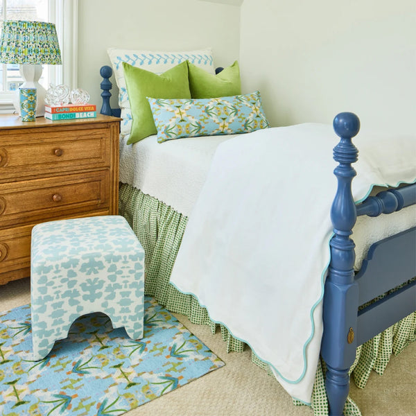 Scalloped Blue + White Duvet Cover by Laura Park Designs, wood dresser, stool, and rug brighten this bedroom.