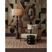 Decorative interior setting with a lamp, mirror, and sofa against a geometric-patterned wall.