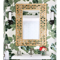 rattan wall mirror on green palm wallpaper