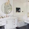 Elegant bathroom with polished marble sink, Mirror Home's round wall mirror, gold fixtures, and walk-in shower.