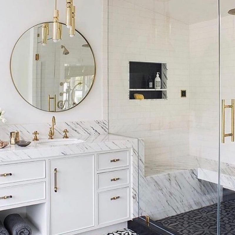 Elegant bathroom with polished marble sink, Mirror Home's round wall mirror, gold fixtures, and walk-in shower.
