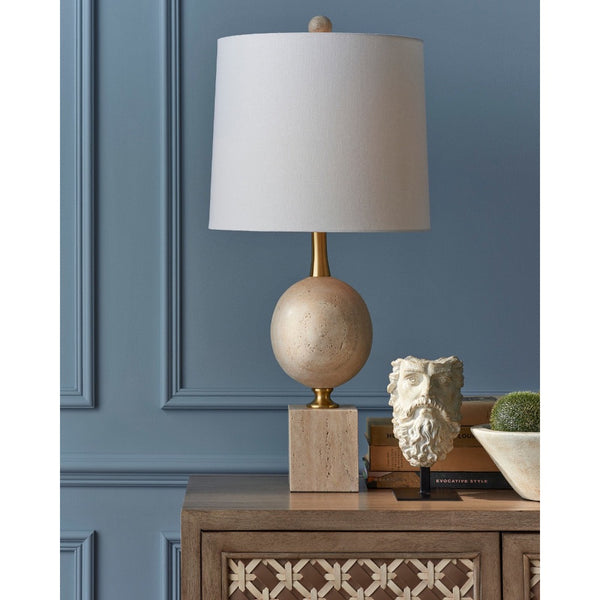 Decorative lamp with a beige base and white shade on a wooden table against a blue wall.
