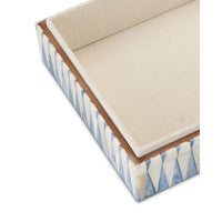 Decorative box with blue and white pattern on a beige cushion