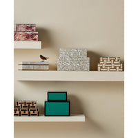 Decorative boxes on a shelf against a beige wall