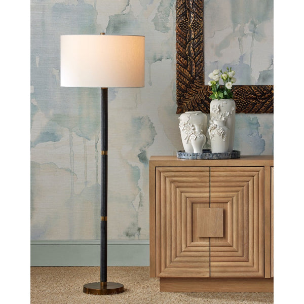 Floor lamp next to a wooden cabinet with decorative items against a patterned wall.