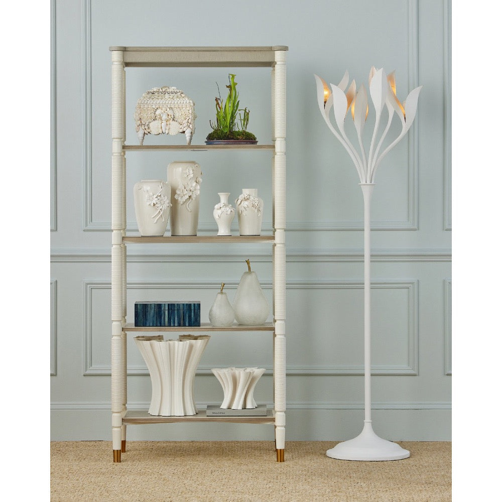 White floor lamp next to a decorative shelf with various items against a light blue wall.