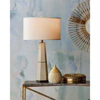 Decorative table with a lamp, small vase, and decorative plate against a textured wall.