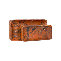 Two rectangular decorative trays with rounded corners, featuring a swirling marbled pattern in orange, brown, and black, set against a plain white background.