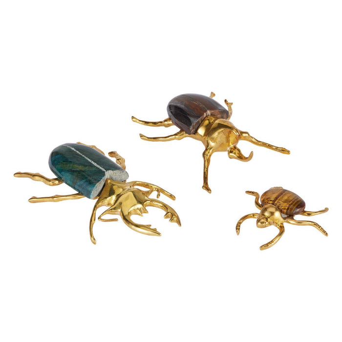 Three beetle-shaped decorative figures in polished gold-tone metal with natural brown beetle wings, displayed on a clean white background.