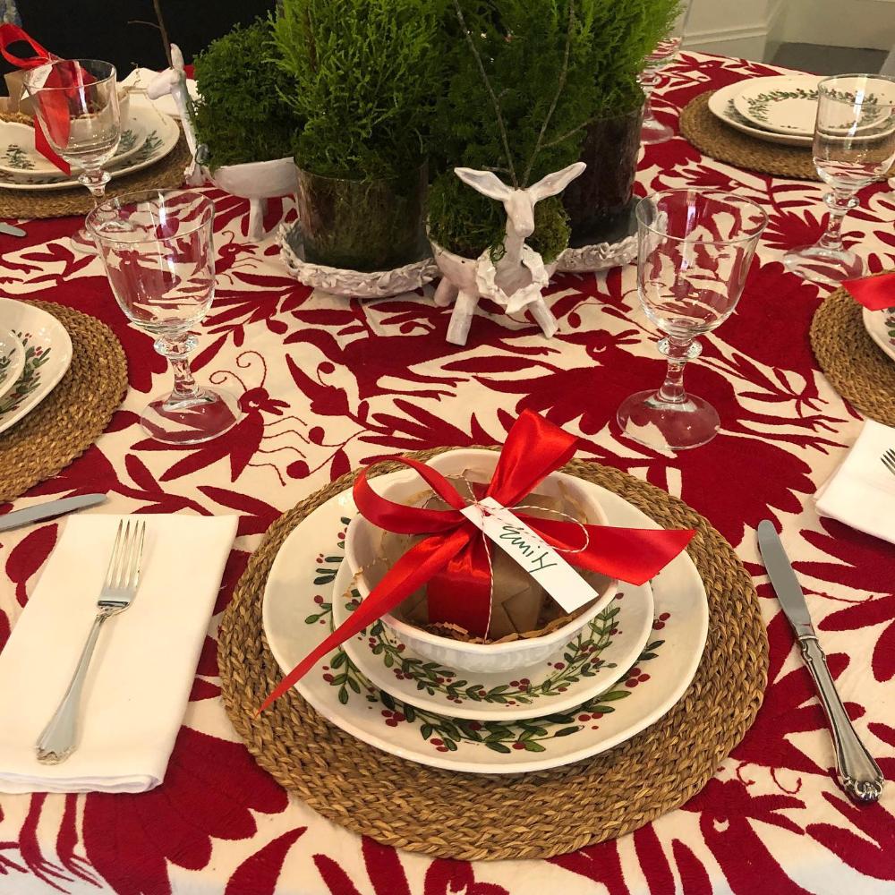 Decorative Christmas table setting with red and white tablecloth, place settings, and festive decor.