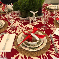Decorative Christmas table setting with red and white tablecloth, place settings, and festive decor.