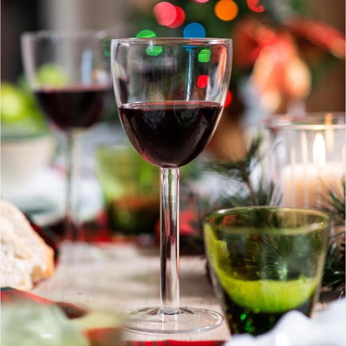Wine glass with red wine on a festive table with blurred lights in the background