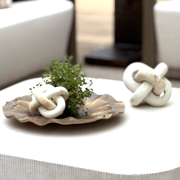 Decorative knot design items including a shell plate with a small plant on a table.