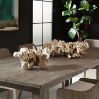 Decorative stone sculptures on a wooden table with chairs and a plant in the background.