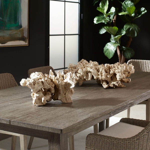 Decorative stone sculptures on a wooden table with chairs and a plant in the background.