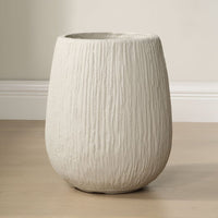 Textured planter on a wooden floor with a neutral background