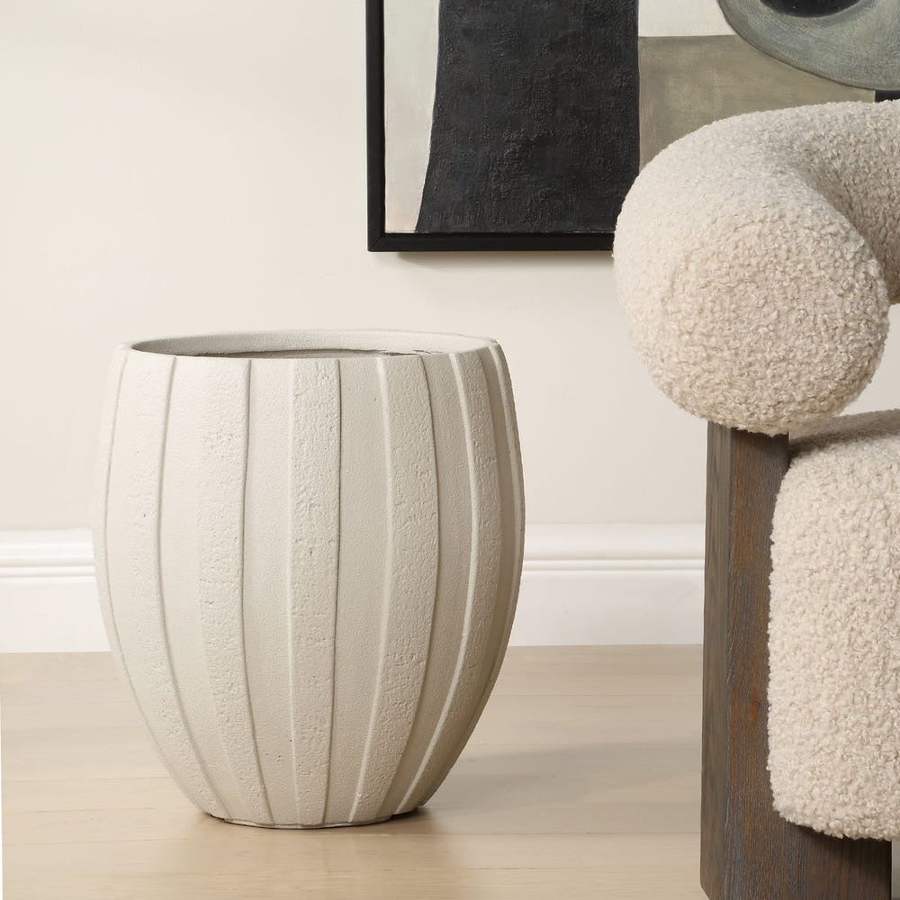 Textured side table in a room with a chair and abstract art on the wall.