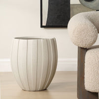Textured side table in a room with a chair and abstract art on the wall.