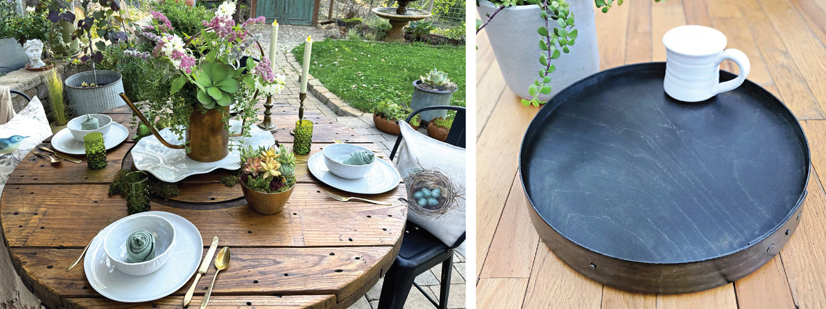 Outdoor table set with floral arrangements and plates with green napkins, next to a wooden tray with a white mug.