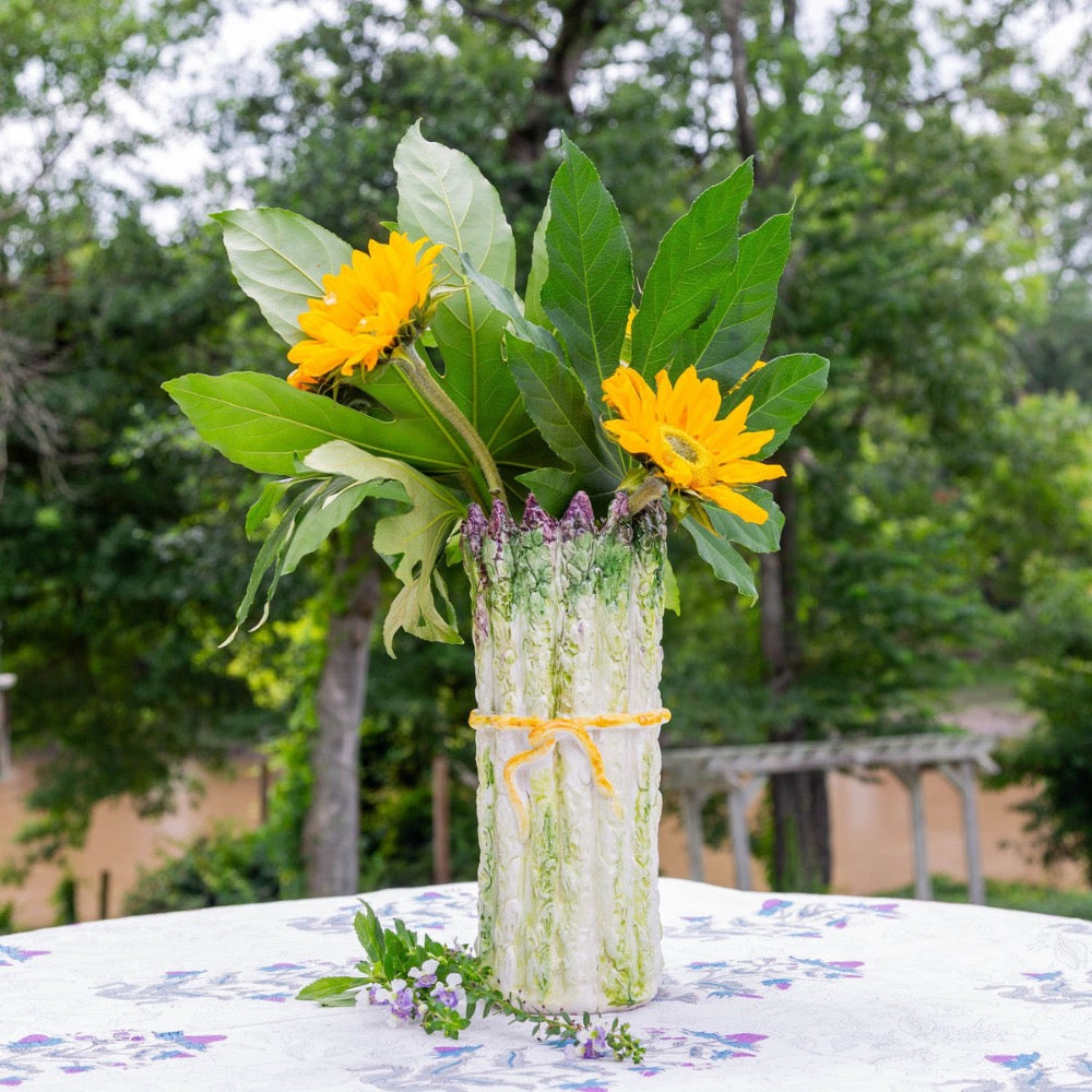 Vase with yellow flowers and green leaves on a table outdoors
