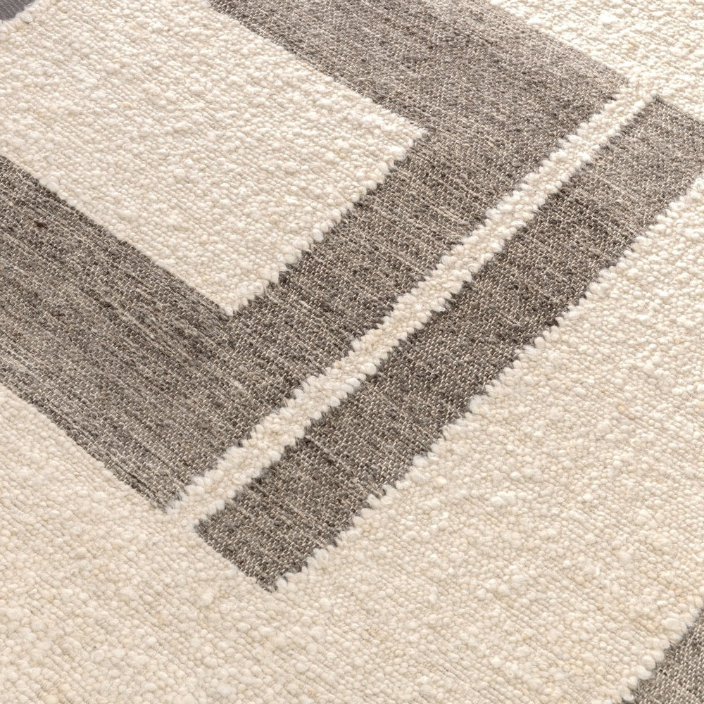 The Classic Home Kavala Charcoal + Ivory Area Rug features geometric cream and gray rectangles with woven texture.