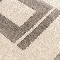 The Classic Home Kavala Charcoal + Ivory Area Rug features geometric cream and gray rectangles with woven texture.