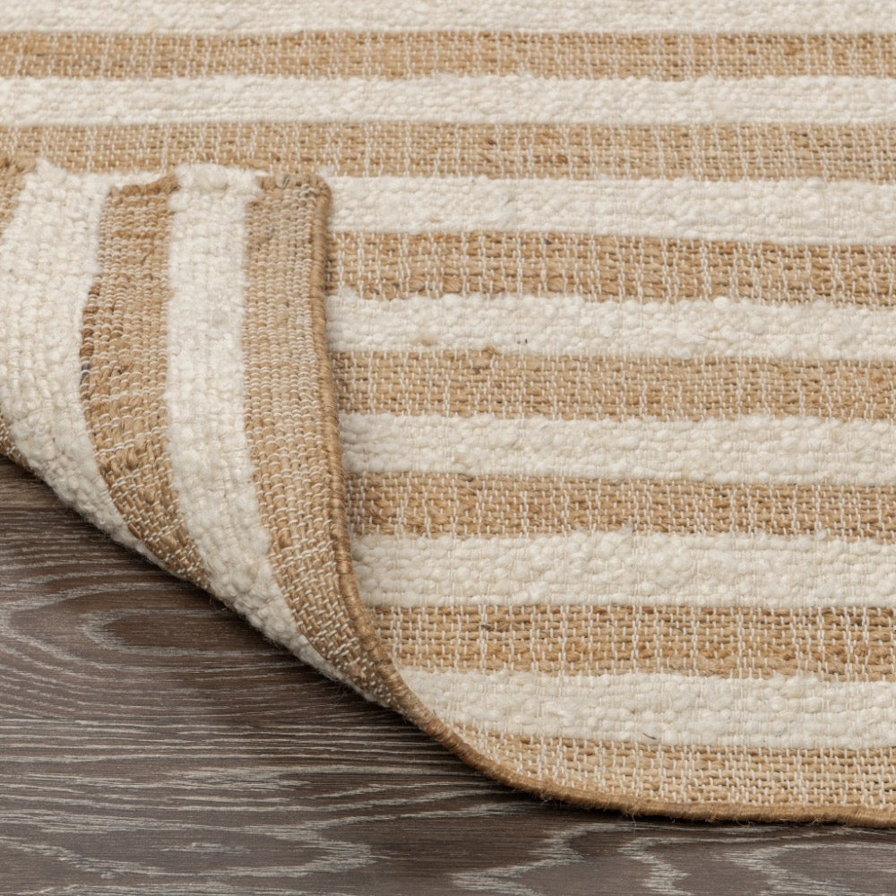 Close-up of a striped rug with beige and brown colors on a wooden floor.