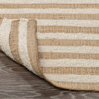 Close-up of a striped rug with beige and brown colors on a wooden floor.