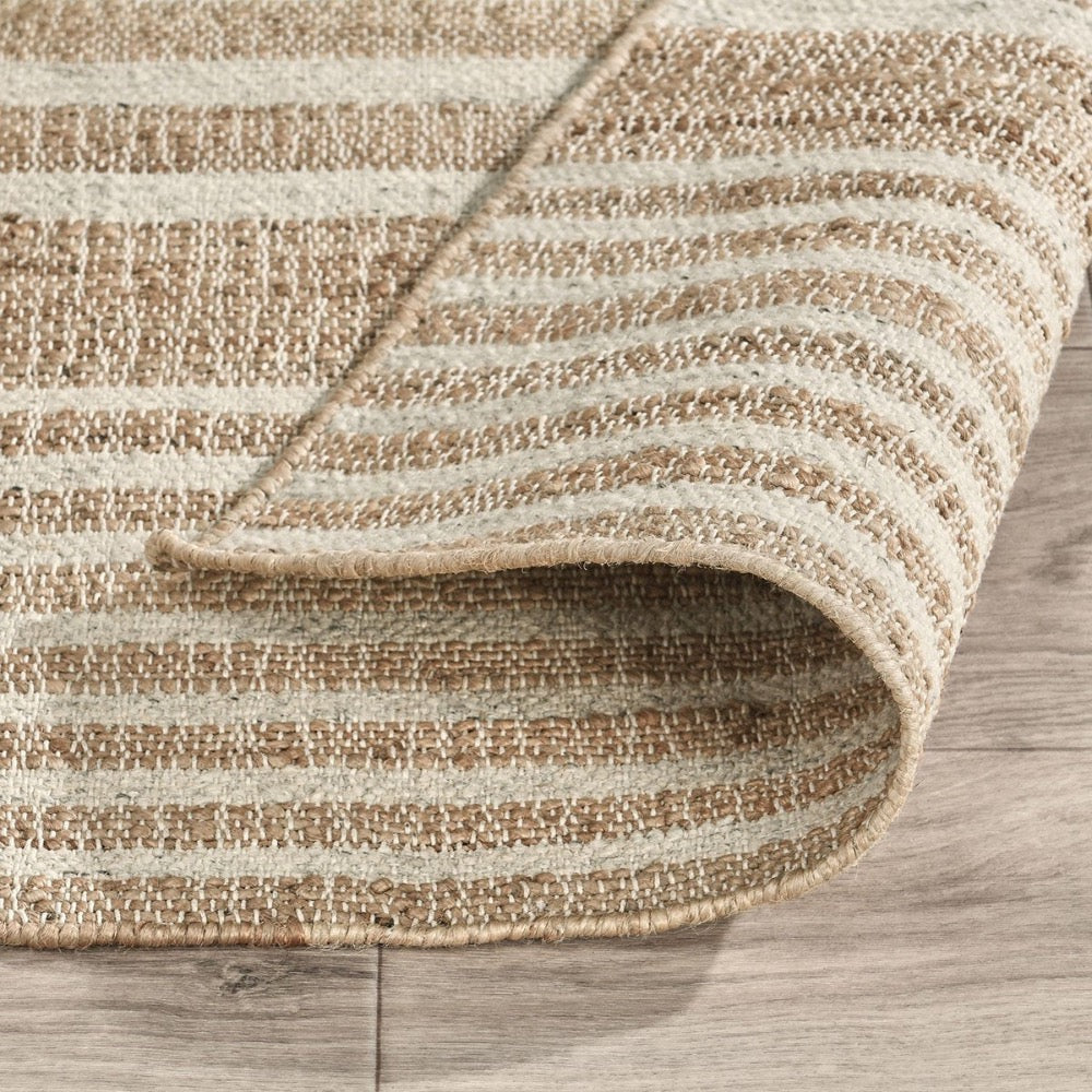 Textured beige and brown striped rug on a wooden floor
