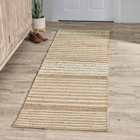 Beige runner rug on a wooden floor with a plant and shoes in the background