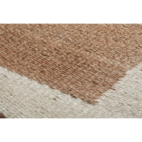 Close-up of a woven rug showing a textured natural tan section meeting an off-white section, with visible weave detail and no visible branding.
