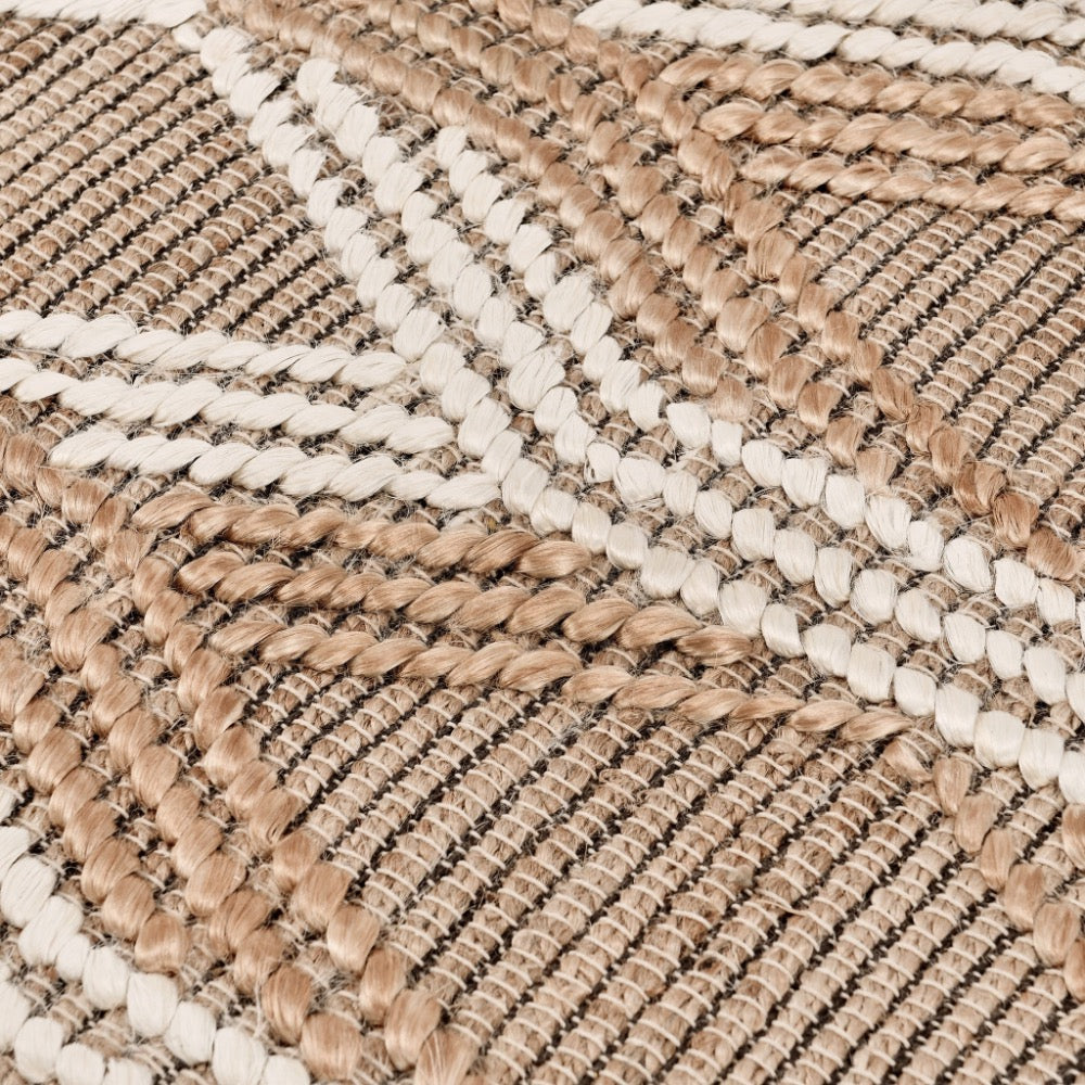 Close-up of a woven rug with a geometric chevron pattern in natural beige, tan, and off-white.