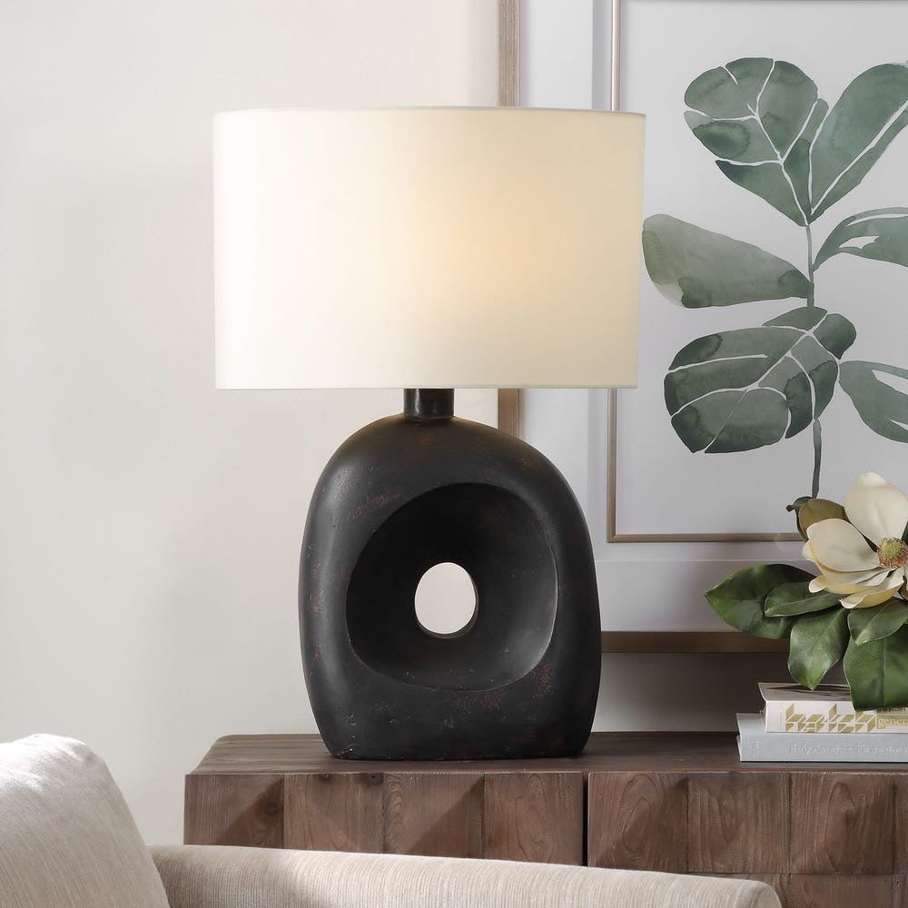 Decorative table lamp with a unique black base on a wooden side table.