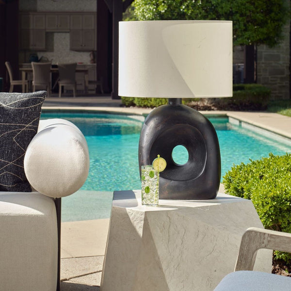 Decorative table with a lamp and glass by a poolside