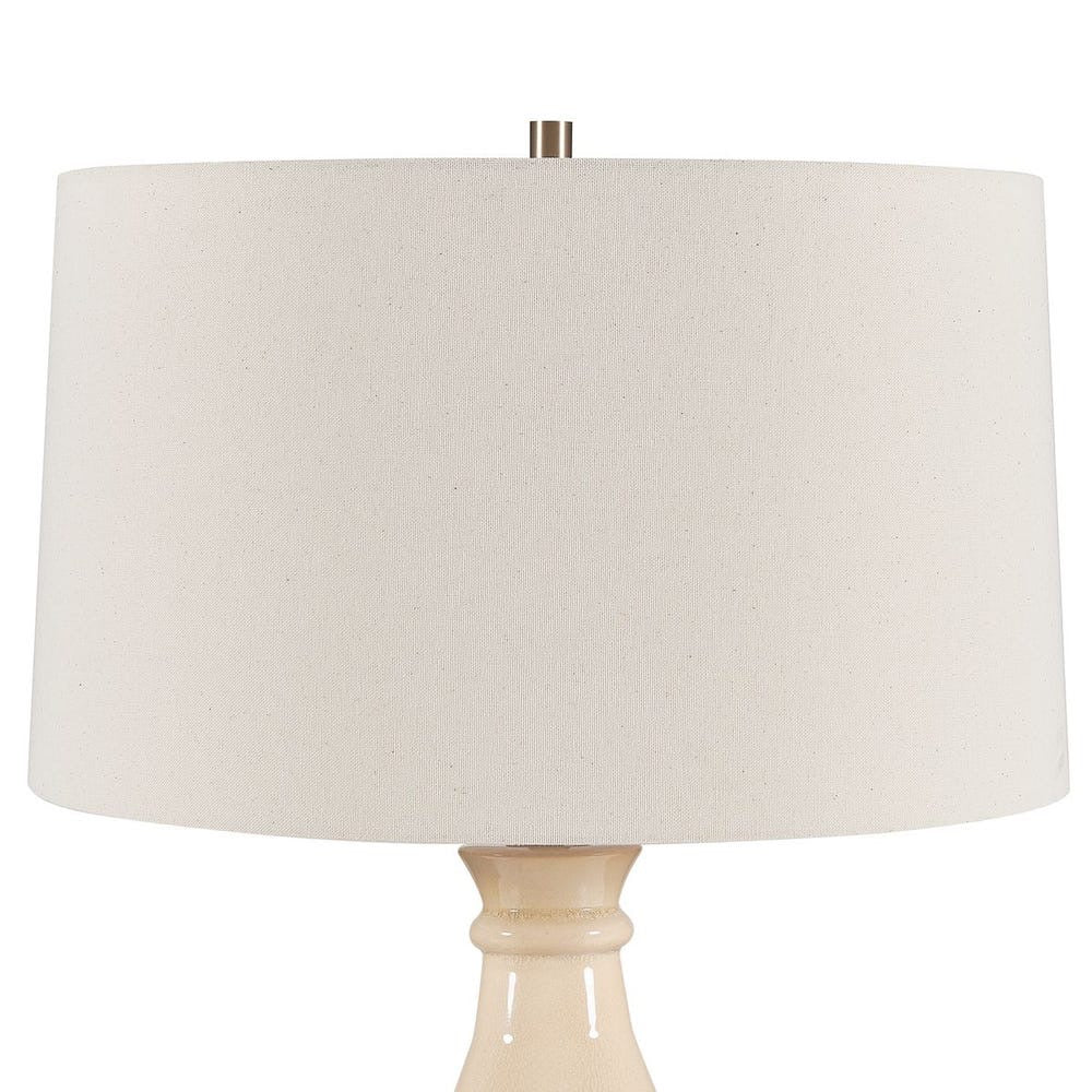Beige table lamp with a large round beige shade on a white background