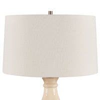Beige table lamp with a large round beige shade on a white background