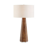 A table lamp with a tapered geometric wood base in a warm brown tone and a large drum shade in off-white fabric, shown against a plain white background.