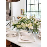 Always Relish Weave Cream Melamine Serving Bowls (set of 2) stacked on a counter with vases of white flowers behind.