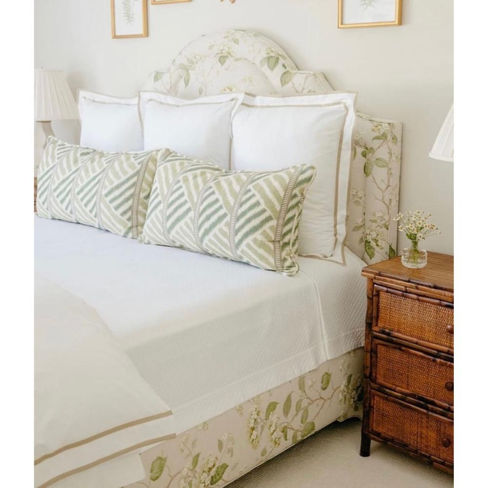A floral bed, green geometric pillows, and Kenian's Tortoise Shell Bamboo + Rattan Bedside Chest enhance style versatility.