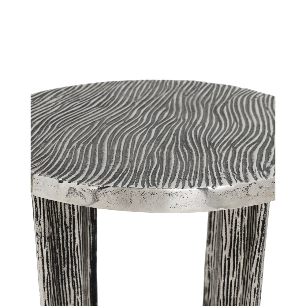 A close-up of a stool with a textured, wavy wood-grain patterned seat and distressed, weathered legs on a plain white background.