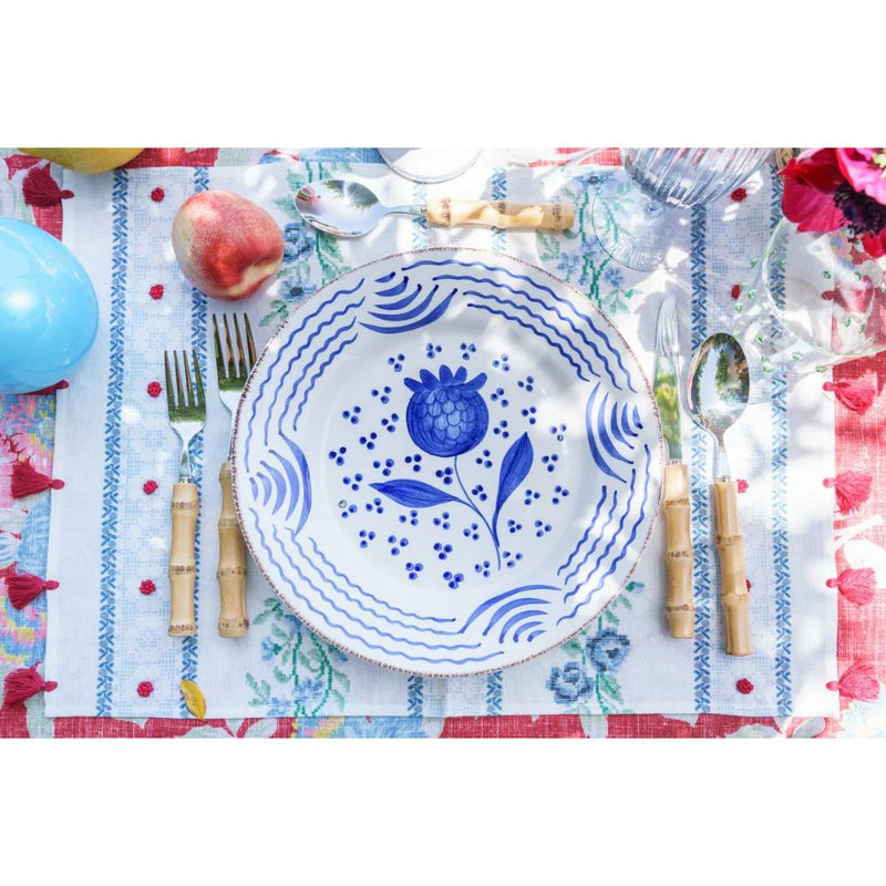 Abigails Casa Nuno Blue Pomegranate Dinner Plates (set of 2) with bamboo cutlery on a vibrant, patterned tablecloth.