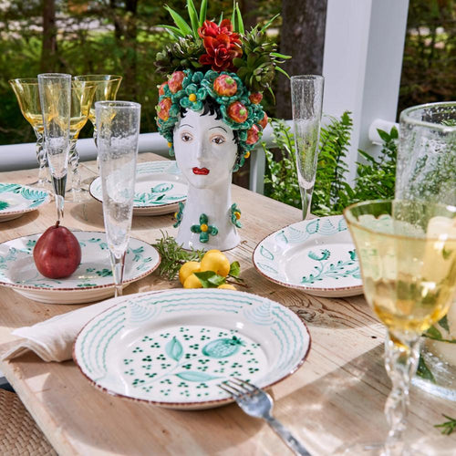 A table set with Abigails Casa Nuno Green Flower Dinner Plates, yellow glasses, and a floral ceramic head vase centerpiece.