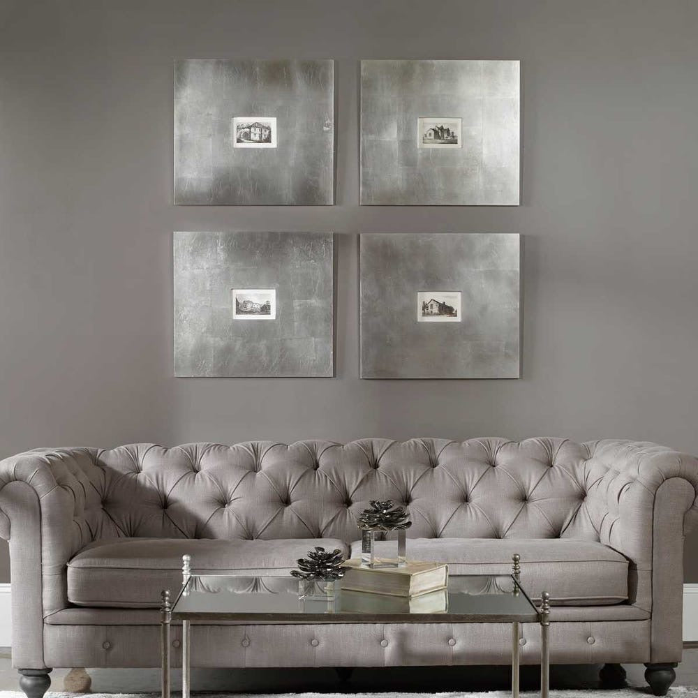 Gray tufted sofa in a living room with four metallic-framed artworks on the wall.